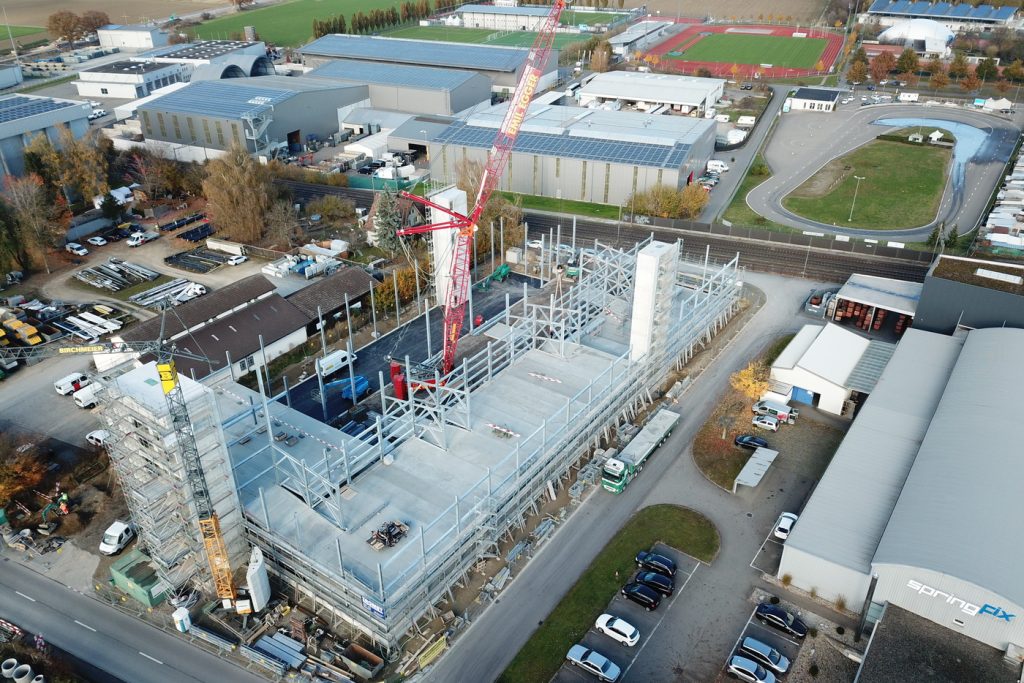 Assembly of steel and concrete elements for a parking garage with the help of a 250-tonne mobile crane.